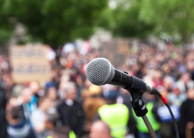 Protest.,Public,Demonstration.,Microphone,In,Focus,Against,Blurred,Audience.