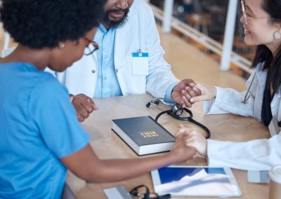 Hands,,Bible,And,A,Medical,Team,Praying,During,A,Meeting